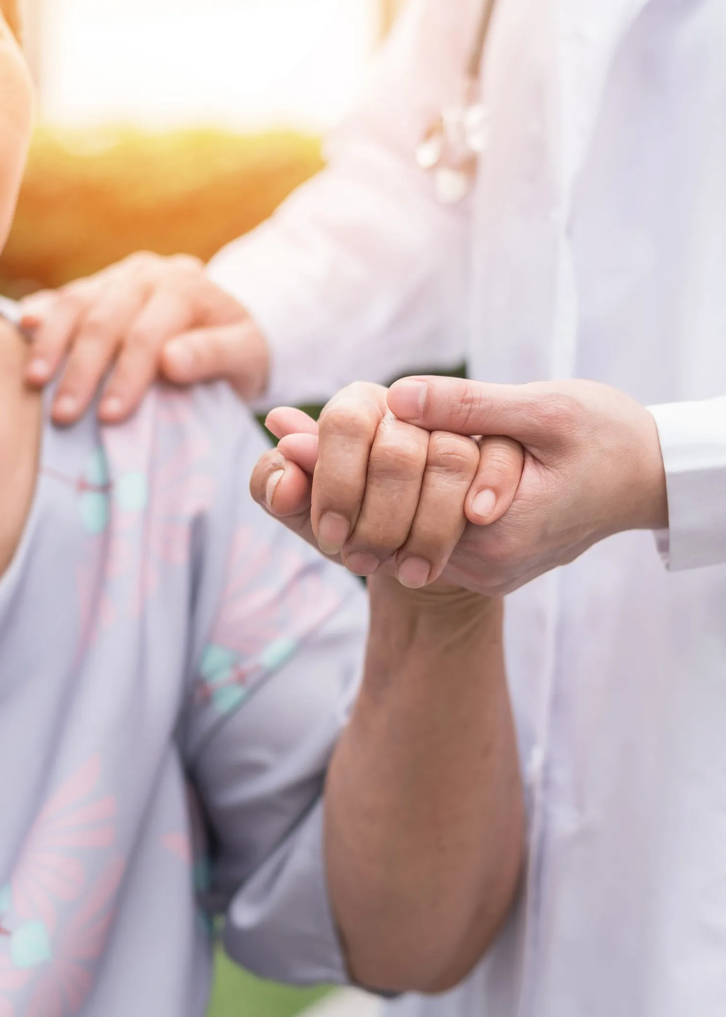 Älterer älterer Demenzpatient (alternde alte erwachsene Person) in einem Hospiz, der die Hand eines geriatrischen Arztes hält, der sich über die medizinische Versorgung durch einen Krankenhauspfleger freut